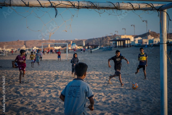Obraz Sur, Oman, January 3, 2020: Children playing soccer on the beach during sunset seen from the goal
