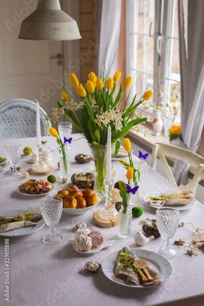 Fototapeta Easter festive spring table setting decoration, eggs in nest, fresh yellow tulips, marshmallows, selective focus