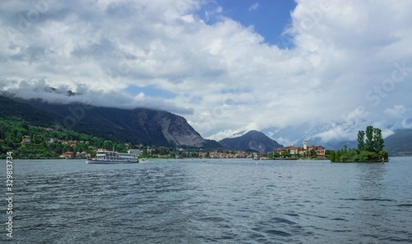 Fototapeta Beautiful view from the Isola Bella embankment . Isola Dei Pescatori and the passing ship. Soft focus, blurry background.