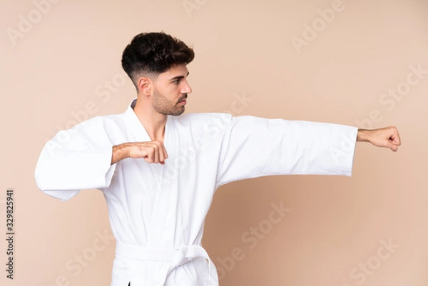 Fototapeta Young man over isolated background doing karate