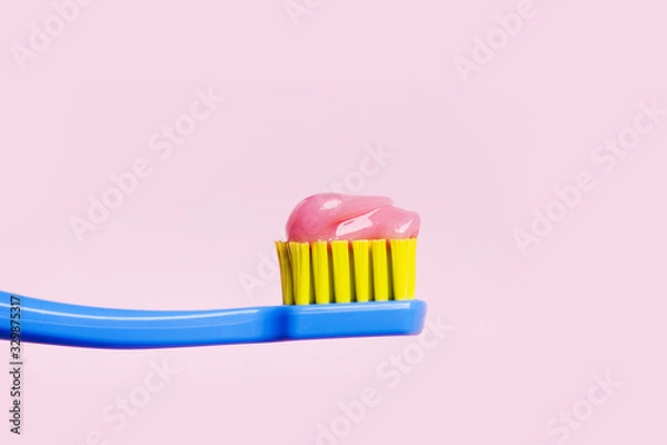 Fototapeta Bright toothbrush with pink paste close-up on a pink background.