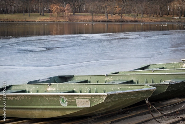 Fototapeta Fishing boats are pulled up onto the shore of a small lake as ice forms, signalling the end of the summer recreation season.