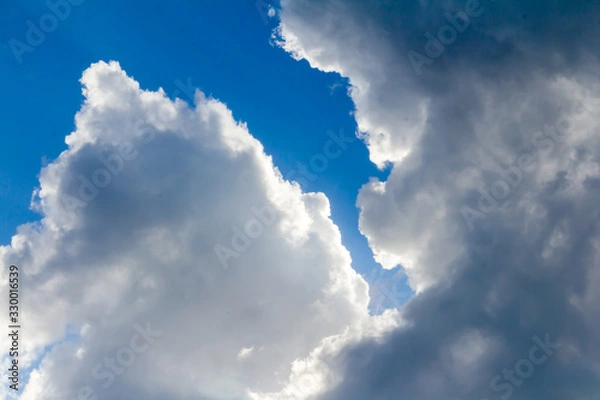 Obraz White and dark grey storm clouds on the blue sky