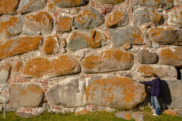 Obraz A girl stands on the background of stone wall of the Solovetsky monastery