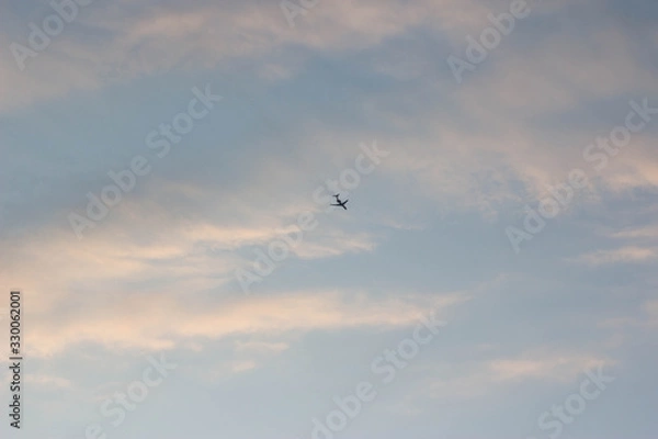 Obraz Sunset over the forest, red, yellow, purple clouds. plane in the sunset sky