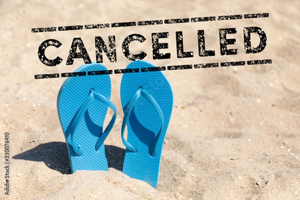 Fototapeta flip flops in the sand and text cancelled - vacation cancel