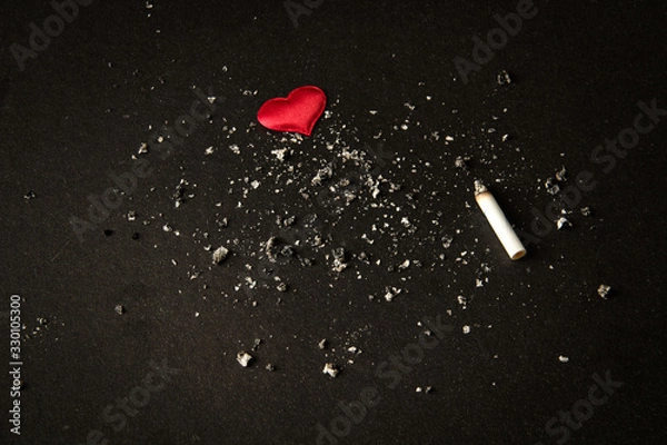 Obraz Smoking.tobacco cigarette butt . red heart on a black background