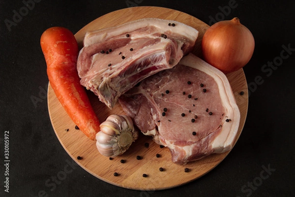 Obraz Meat. Raw pieces of pork with and pepper, carrots, garlic, onions. on a wooden board on a black background