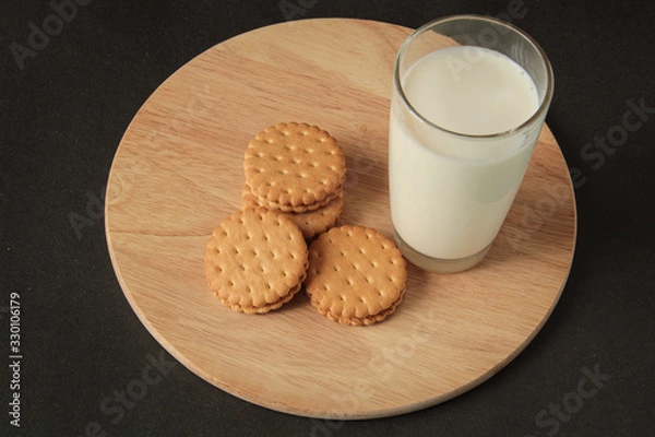 Obraz cookies and a glass with milk. cookies with cream, on a wooden board. Black background