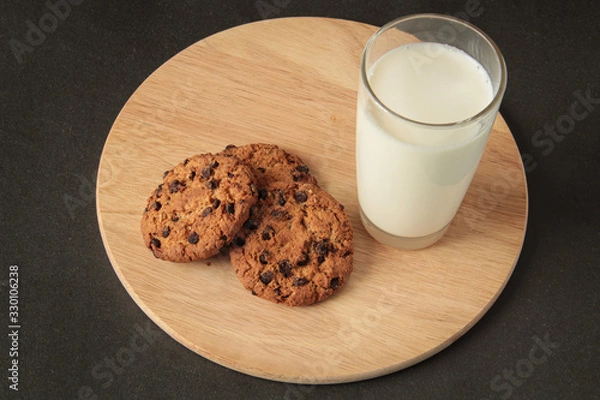 Obraz glass of milk and oatmeal cookies on a wooden board