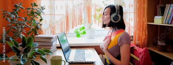 Obraz Kobieta w słuchawkach siedzi z przodu laptopa i oddycha. Koncepcja medytacji audio online.