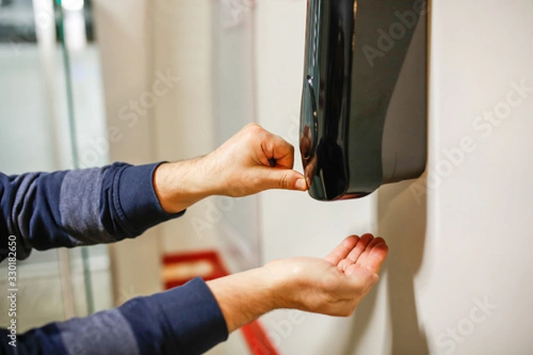 Obraz Two Hands under the automatic alcohol dispenser.
