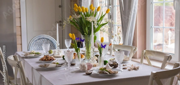 Fototapeta Easter festive spring table setting decoration, eggs in nest, fresh yellow tulips, marshmallows, selective focus banner