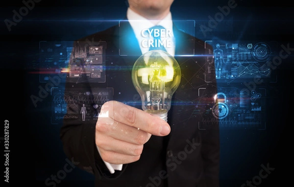 Fototapeta Businessman holding lightbulb with CYBER CRIME inscription, online security idea concept