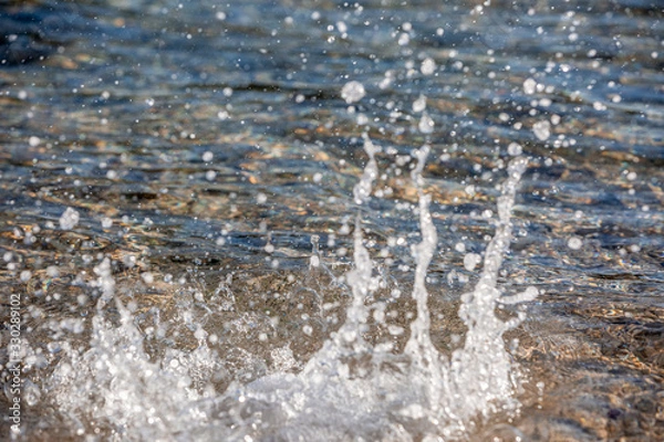 Obraz Water spray produced by wave on beachline, selective focus on water splashes