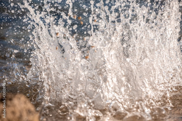 Obraz Water spray produced by wave on beachline, selective focus on water splashes