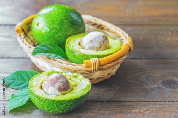 Fototapeta ripe avocados in a basket and on the table close-up. background with avocado. avocado halves and green leaves close-up.