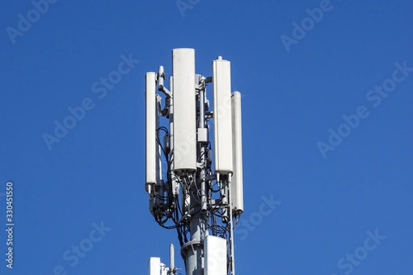 Fototapeta Telecommunication tower of 4G and 5G cellular. Cell Site Base Station. Wireless Communication Antenna Transmitter. Telecommunication tower with antennas against blue sky.