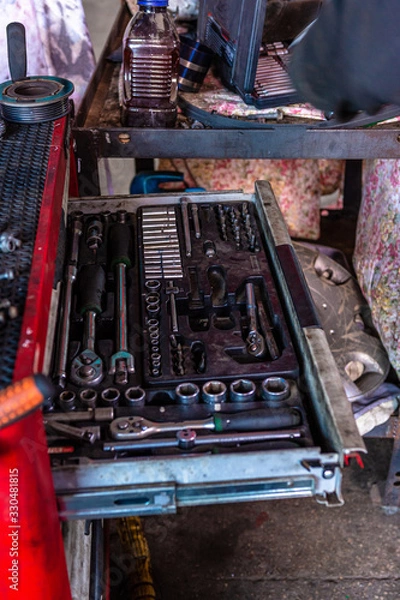 Fototapeta The mechanic in the car service picks up a tool for repairing the car