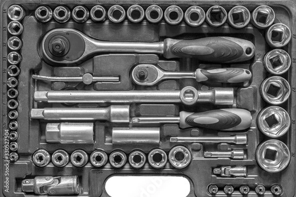 Fototapeta Black and white men tools background. Worker tools and equipment close-up. A set of wrenches and screwdrivers are laid out in the cells of the box.