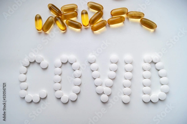 Obraz Лекарства таблетки на белом фоне белые и желтые слово ковид