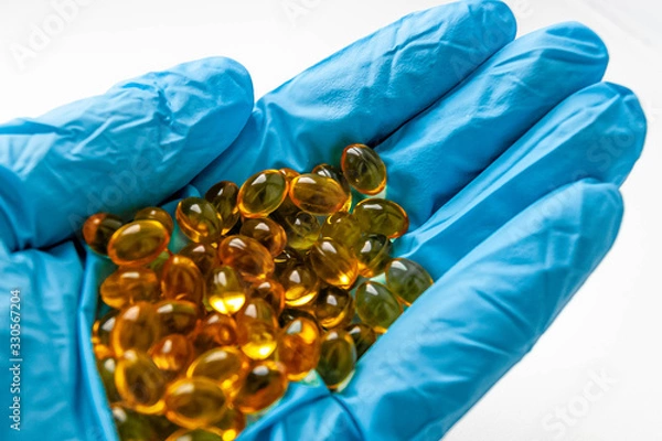 Obraz Медицина, лекарства рука в перчатке держит таблетки на белом фоне