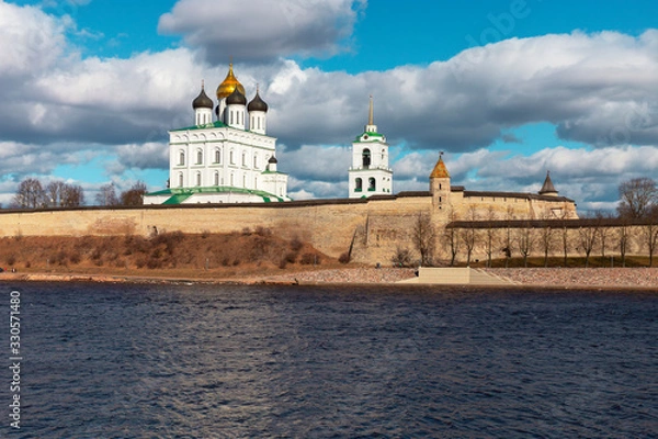 Fototapeta Spring panorama of an old medieval fortress standing on the river Bank. Pskov, Russia.