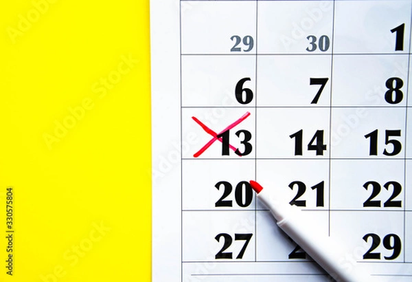 Fototapeta Numbers on the calendar crossed out with a red cross in macro on a yellow background. Calendar for plans, notes, meetings. Business calendar.  Marker for notes on the calendar. In the foreground.