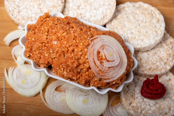 Fototapeta veganes mett, Brotaufstrich mit Zwieben umgeben von Reiswaffeln, Zwiebeln und Tomatenmark, in einer Schale auf einem Holzbrett, Textfreiraum