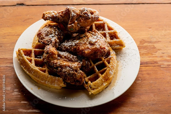 Fototapeta Chicken & waffles. Classic American Diner Style Breakfast or Brunch menu item favorite. Crispy homemade fried chicken on top of home buttermilk waffles topped with butter and maple syrup. 