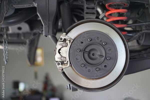 Fototapeta Brake disk and detail of a wheel hub. Disc brake of the vehicle for repair, in process of new tire replacement. Car brake repairing in garage.Close up.