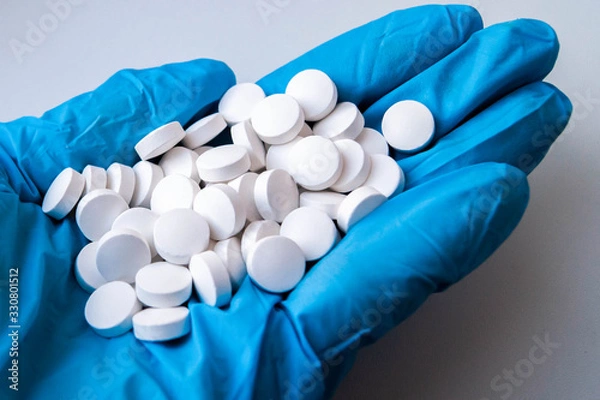 Obraz рука доктора в синей медицинской перчатке держит горсть таблеток