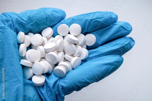 Obraz рука доктора в синей медицинской перчатке держит горсть таблеток