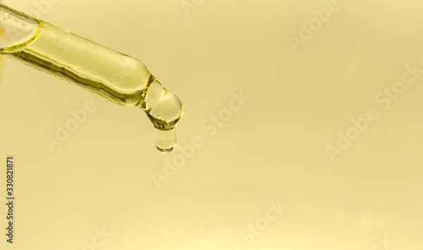Fototapeta On a yellow background a glass pipette with cannabis oil. A drop drops from the end of the pipette. Concept - illicit drug use