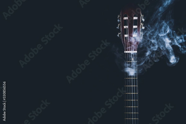 Fototapeta Acoustic guitar in smoke on the black background. musical instrument. strings on the guitar neck