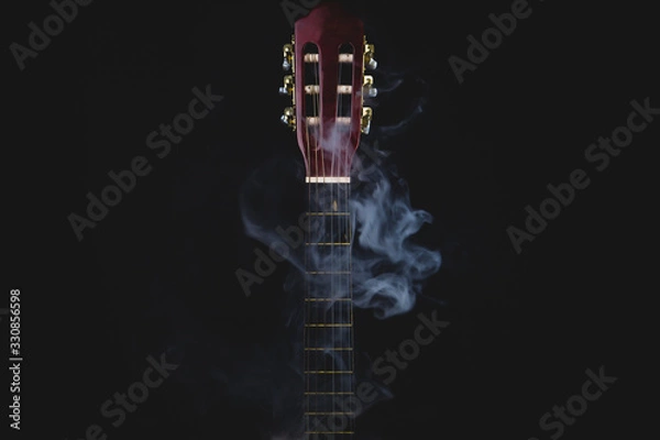 Fototapeta Acoustic guitar in smoke on the black background. musical instrument. strings on the guitar neck