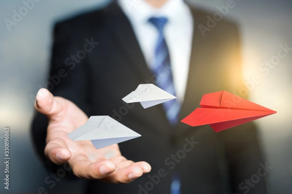 Fototapeta Red paper plane thrown by the hands of a businessman, leadership and STARTUP business concept