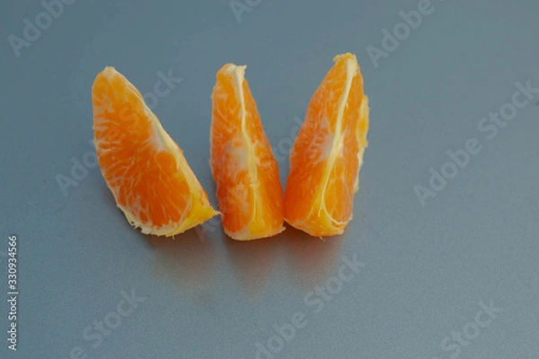 Fototapeta Three slices of mandarin on a blue background