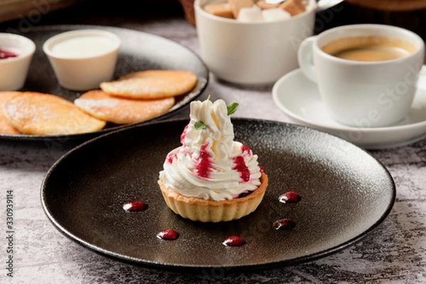 Fototapeta Cupcakes with whipped white vanila cream with a cup of black coffee americano for breakfast, background with copyspace. Food and drink concept.