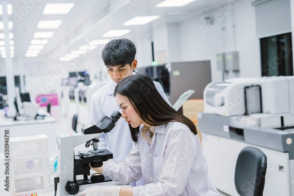 Fototapeta Two  medical  scientist working in Medical laboratory , young female scientist looking at microscope. select focus in young  female scientist