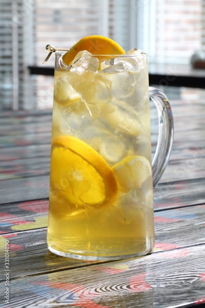 Fototapeta Glass jug with lemonade from oranges and lemons on a wooden table