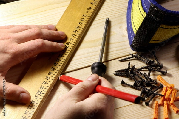Fototapeta Different tools on a wooden background. Carpenter tools on a table. Hand holding riler and pencil.
