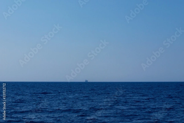Fototapeta Ship sails in endless sea, shape in fog. Journey to blue.