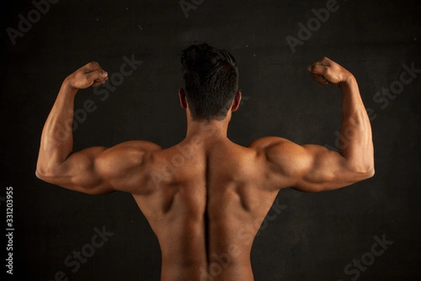 Obraz Tanned trainer body builder posing back biceps athletic body