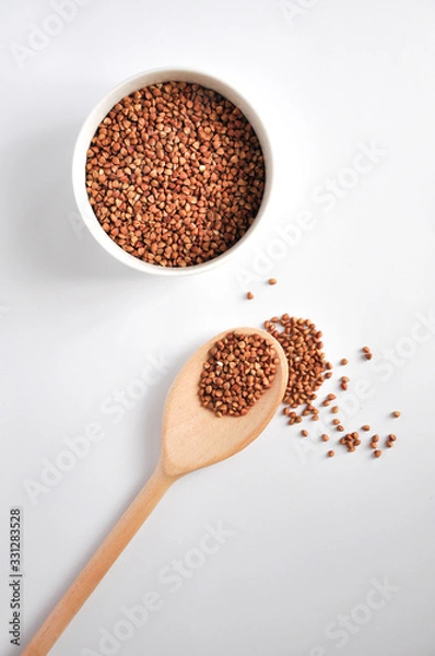 Fototapeta buckwheat on a plate and spoon isolated background
