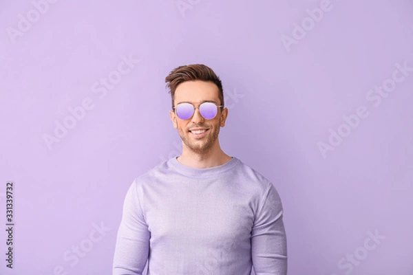 Fototapeta Young man with stylish sunglasses on color background