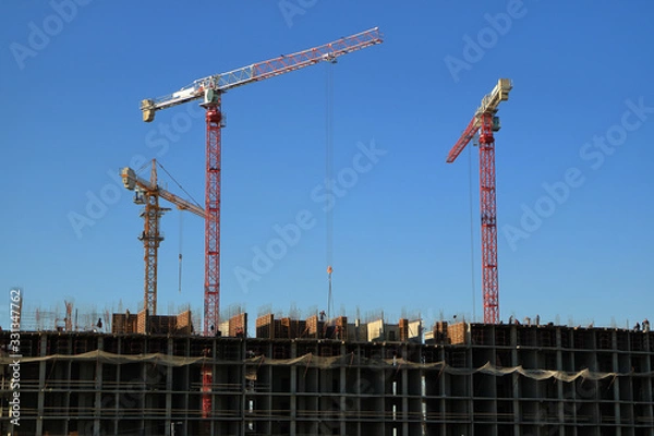 Fototapeta Tower cranes are working on the construction of a new house. Lifting crane.