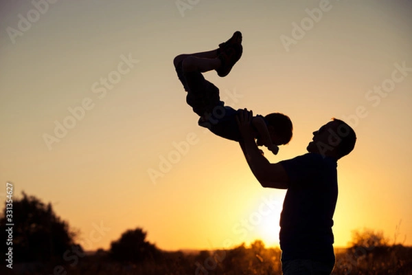 Obraz Father and son playing in the park at the sunset time.