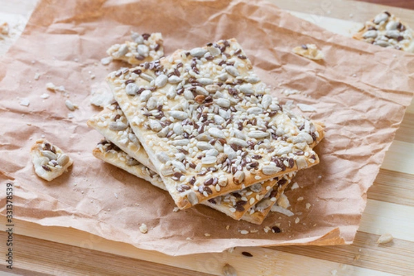 Fototapeta Square crackers with flax, sesame and sunflower seeds on butter papers