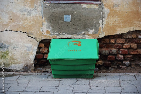 Obraz Green plastic sand box standing on pavement beside old crumbly wall